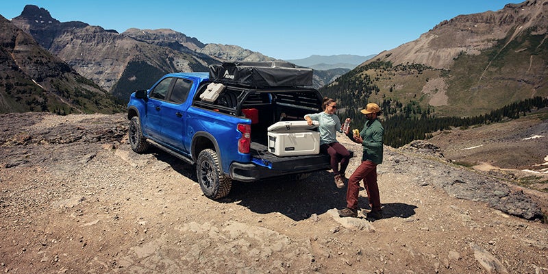 Blue Chevrolet Colorado truck kicking up sand on a desert dune
